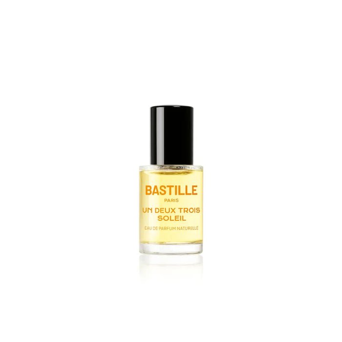 A bottle of 'Un Deux Trois Soleil EDP' by Bastille, with a brown cardboard packaging behind it. The bottle has a black cap and the brand name is displayed prominently on the front.