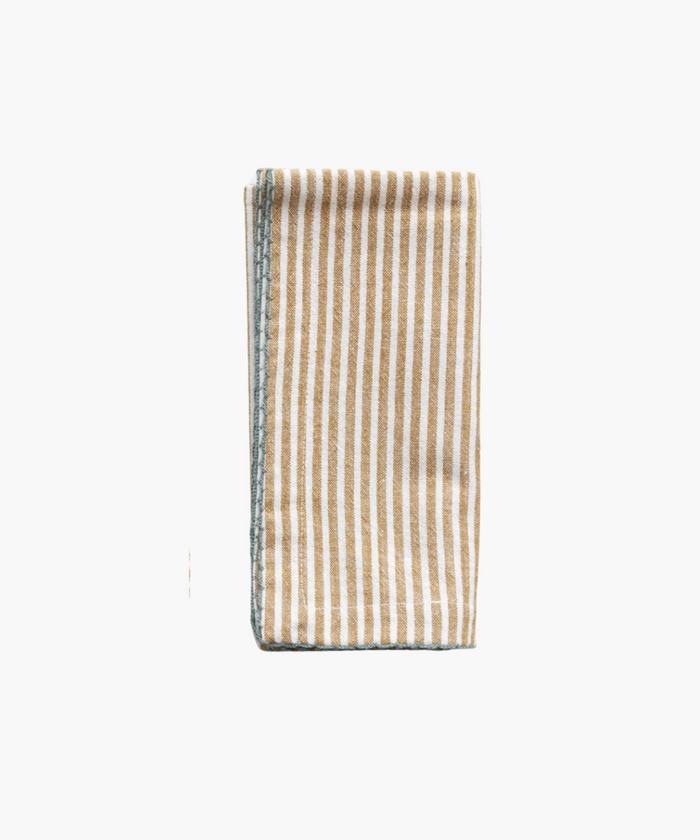 A neatly folded napkin with vertical beige and white stripes. The edges are sewn with teal stitching, giving a simple, elegant, and orderly appearance.
