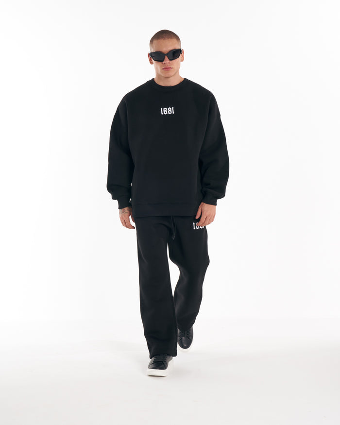 Martin Valen 1881 oversized black sweatshirt with 3D embroidery, front mid-body view of model walking