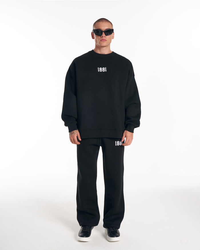 Martin Valen 1881 black tracksuit with oversized embroidered sweatshirt, full-length view of model standing and walking