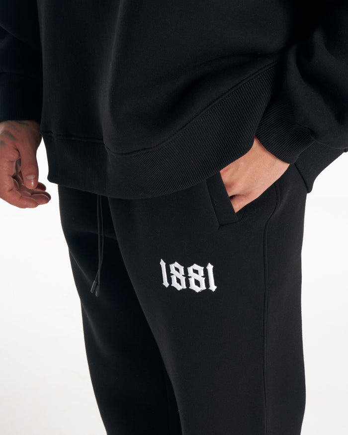 Martin Valen 1881 black tracksuit set worn, full-length view showing straight-leg trousers and black sneakers with white soles