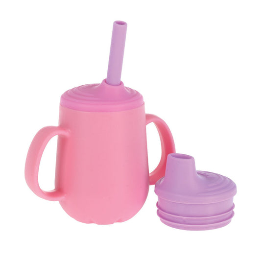 The Nuby US 3-Stage Training Cup Set with Handles in pink and purple is shown with a removable no-spill straw lid and two handles. A separate purple spout lid is placed next to the cup.