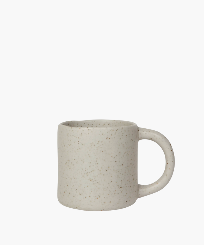 A speckled beige ceramic mug with a smooth surface and a curved handle. The mug has a rustic, minimalist design, evoking a cozy and comforting feel. | Wildwood Home Co.