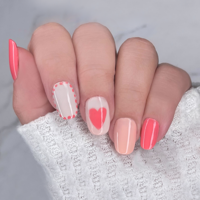 Better Than Roses coral pink manicure with heart accent nail art on a light skin tone