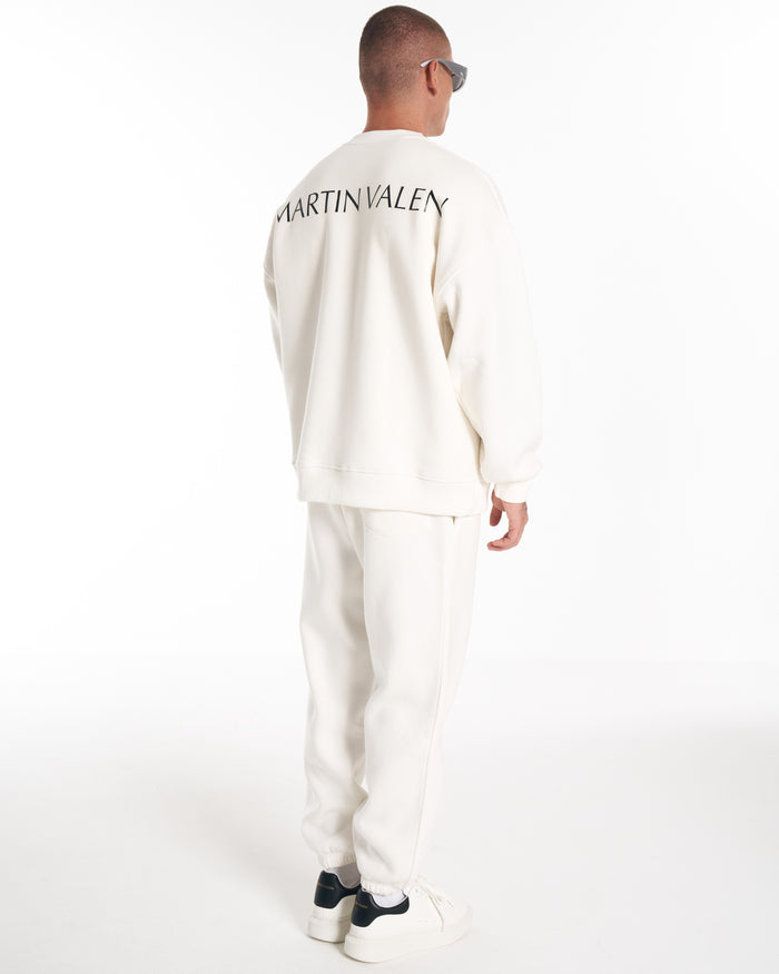 Close-up of Martin Valen white sweatshirt ribbed crewneck from side, partial brand logo visible on chest