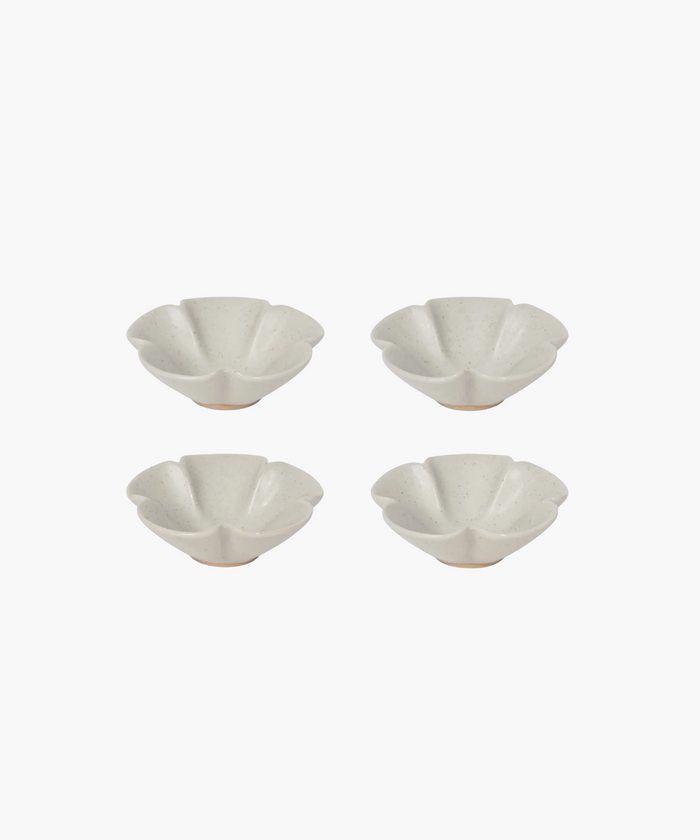 Four white, flower-shaped ceramic bowls with speckled texture are arranged in a symmetrical grid on a plain white background. | Wildwood Home Co.