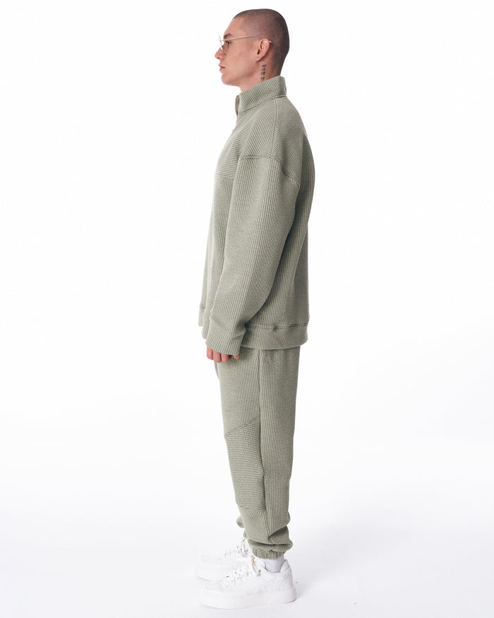 Martin Valen khaki high‑collar half‑zip tracksuit, full rear view including matching trousers and white sneakers