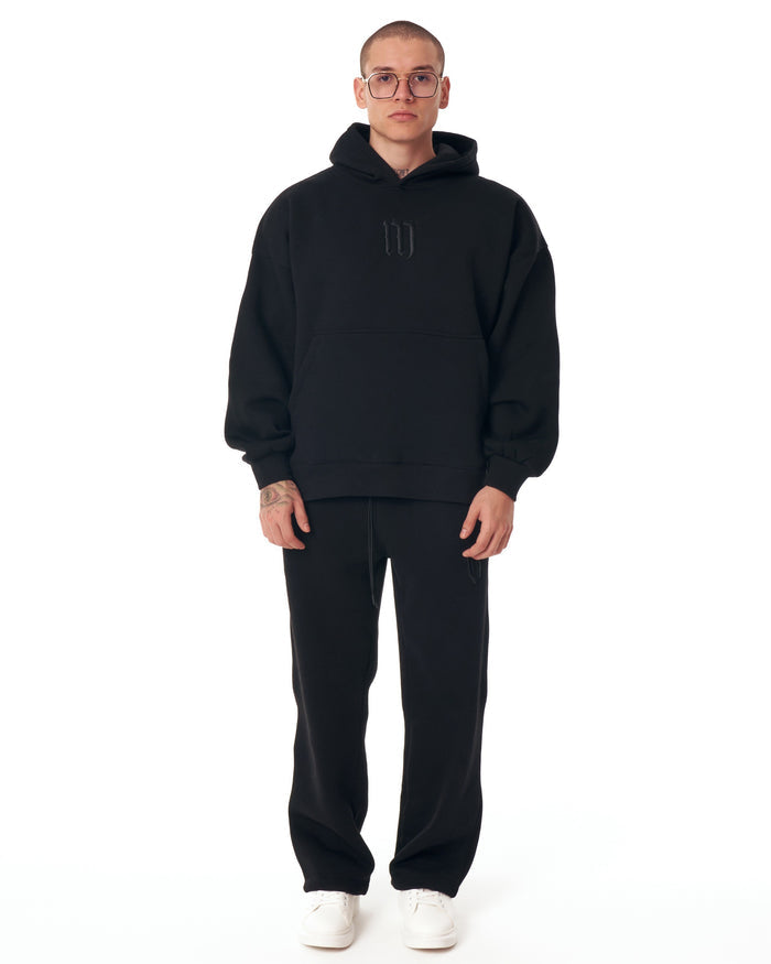 Martin Valen Insignio black hoodie tracksuit walking full-length view, loose jogger pants and white sneakers visible