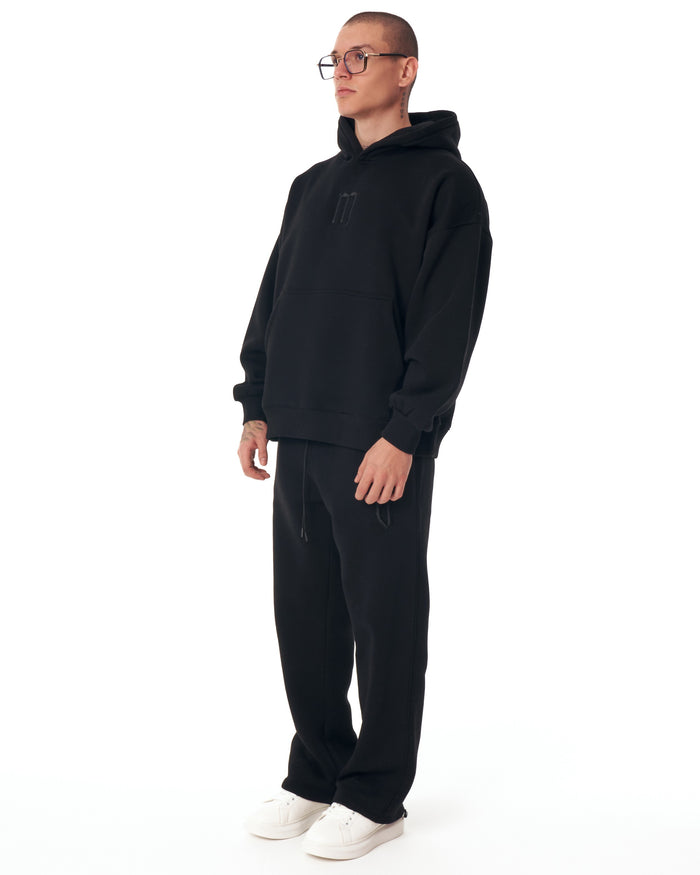 Martin Valen Insignio oversized black hoodie mid-torso front view, model facing camera highlighting central embroidery and voluminous sleeves