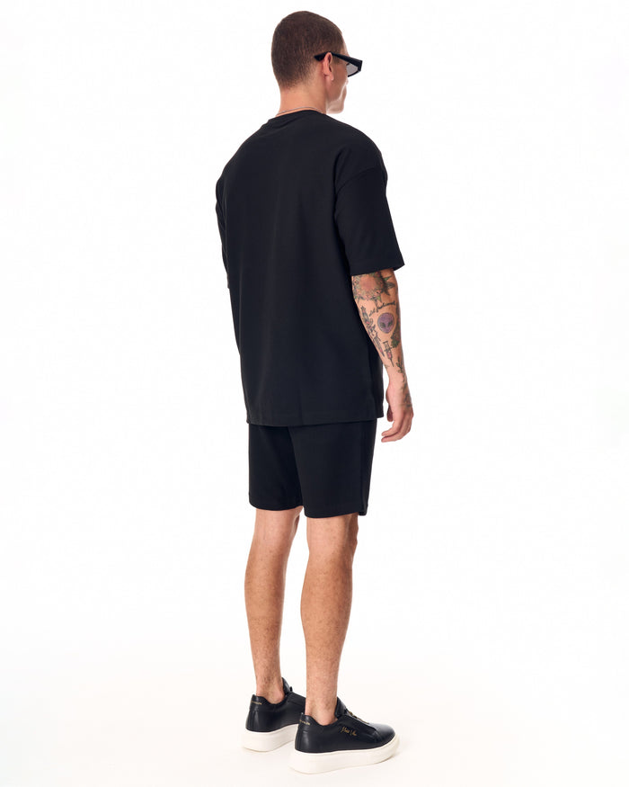 Martin Valen men's full black short tracksuit, three-quarter view showing black zip-front sneakers with white soles