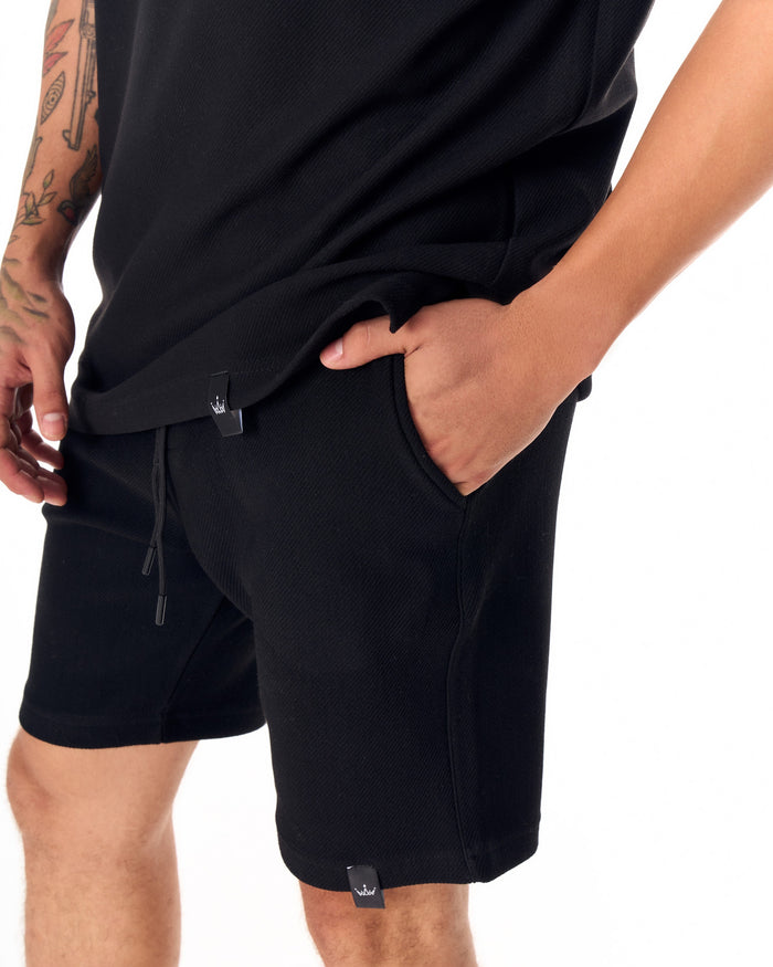 Martin Valen men's full black short tracksuit, waist close-up with hand in pocket and visible drawstring