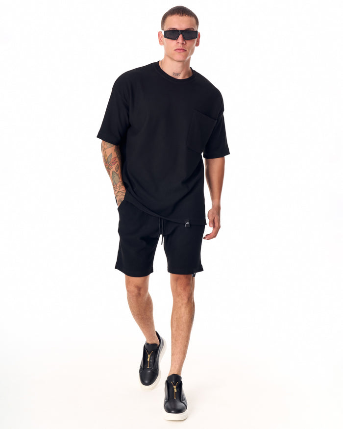 Martin Valen men's full black short tracksuit, side view of legs with branded tag on hem