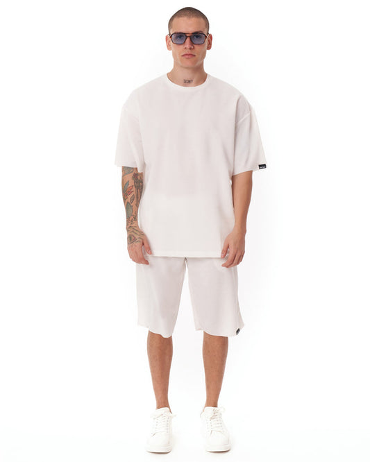 Martin Valen men's oversized white shortsuit, front view showing light fabric and black logo tag on sleeve.