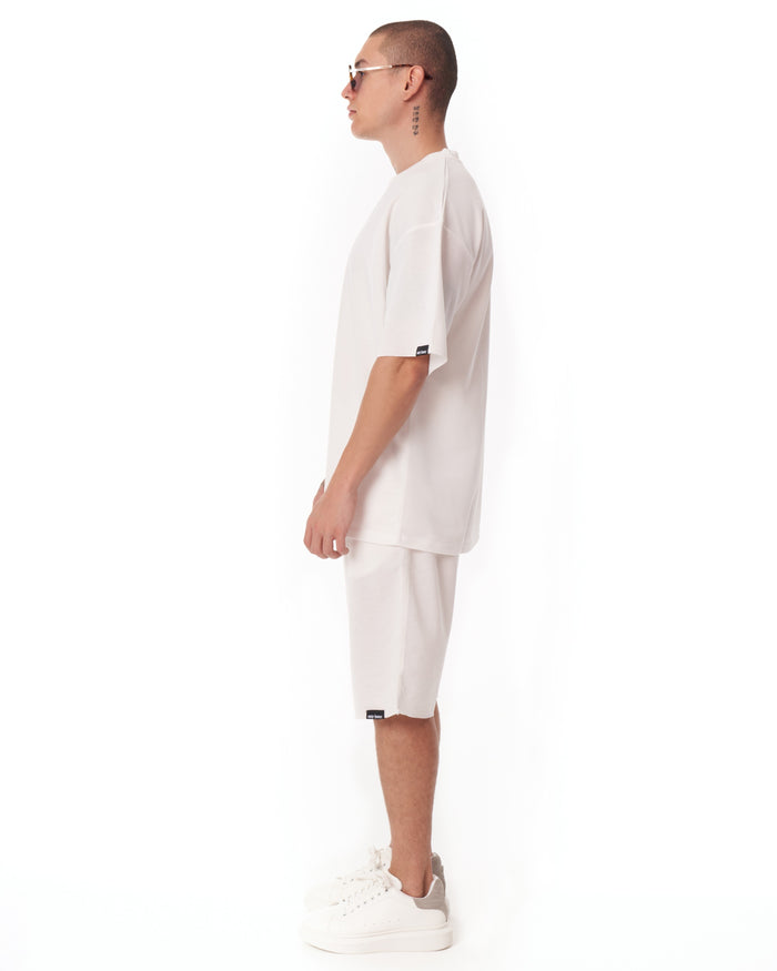 Martin Valen men's white oversize shortsuit in profile view, light fabric with a small black sleeve tag