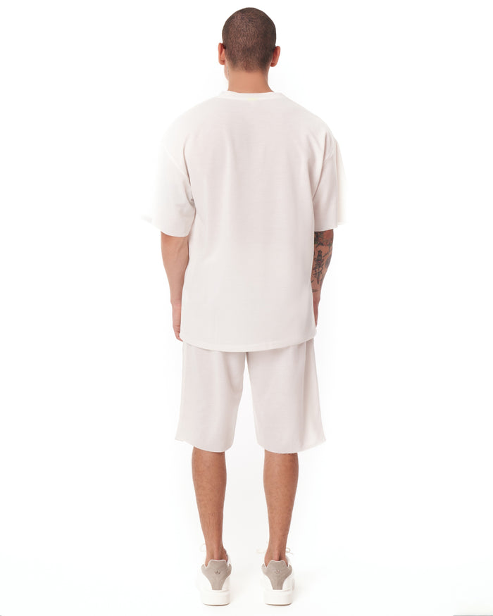 Martin Valen men's white oversize shortsuit three-quarter back view showing t‑shirt back and visible arm tattoos