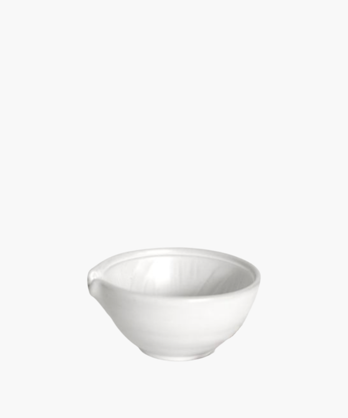 Simple white ceramic mixing bowl with a small spout, reflecting soft light. The bowl is placed against a plain, light gray background. | Wildwood Home Co.