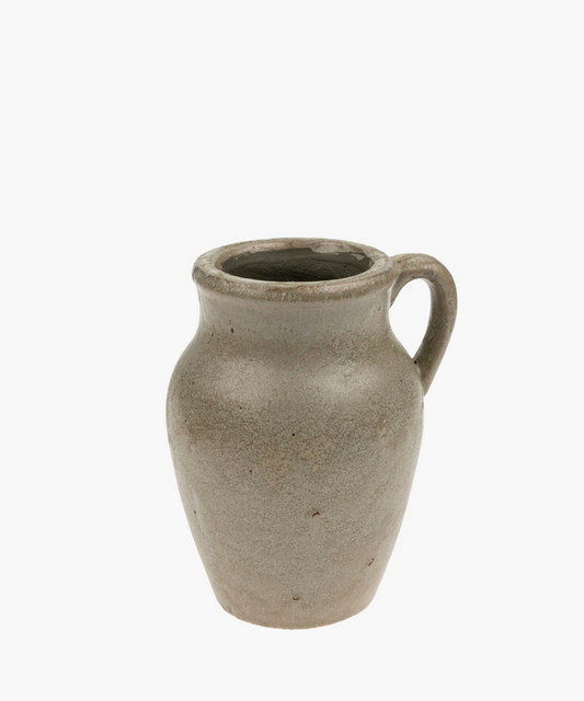 A rustic, gray ceramic pitcher vase with a single handle. Its simple design and smooth texture convey an antique, handmade aesthetic. | Wildwood Home Co.