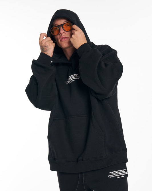 Martin Valen Rumi oversized black printed hoodie, close-up front view with hood up and orange-tinted glasses