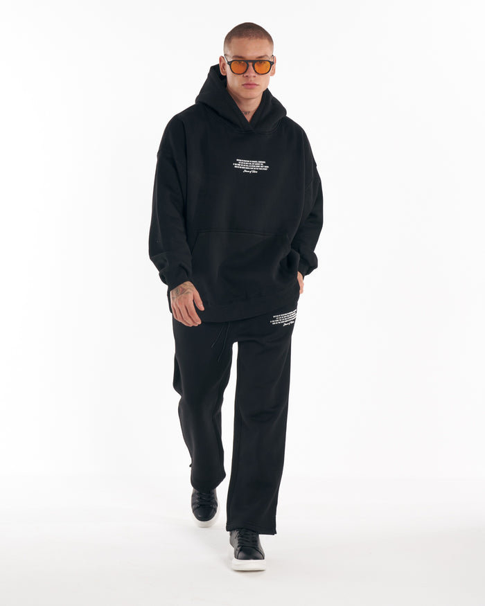 Martin Valen Rumi black printed tracksuit, waist-level view showing kangaroo pocket and small white printed text