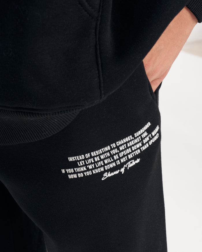 Martin Valen Rumi oversized black hoodie, three-quarter view with raised hood and small white print on the thigh