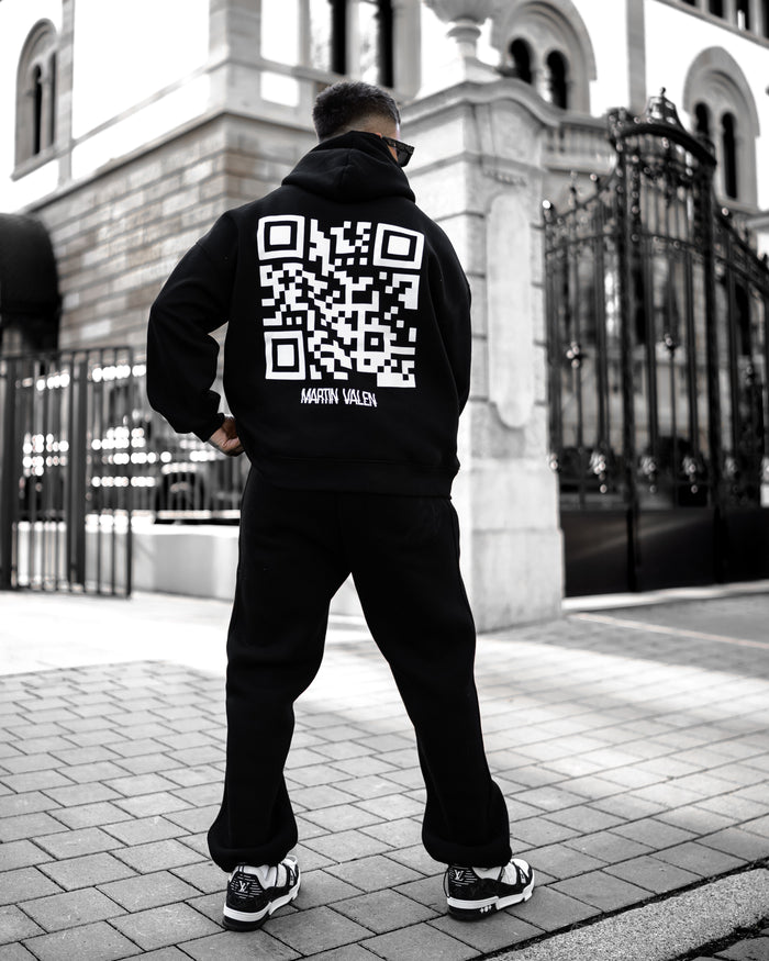 Martin Valen Sigilio oversized black hoodie seen from rear, large white QR code printed on the back, three-quarter view.
