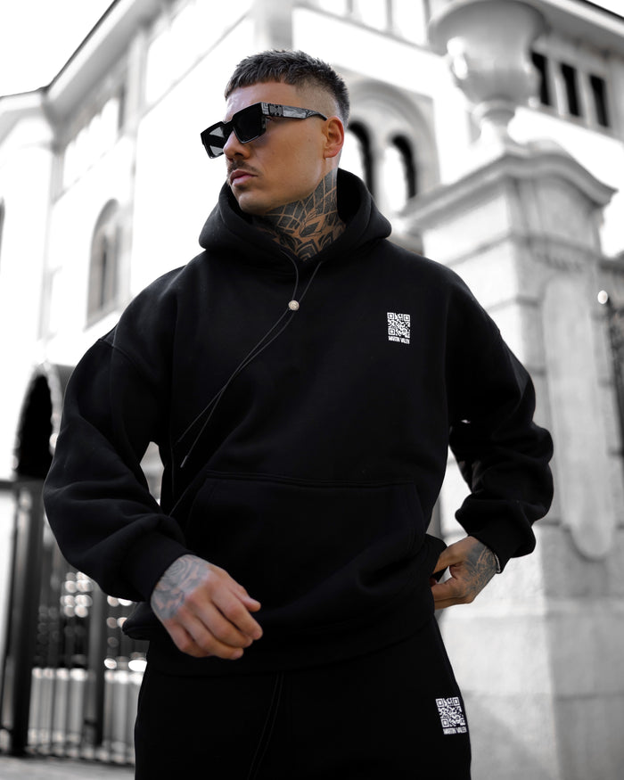 Martin Valen Sigilio oversized black hoodie seen three-quarter view, white QR code logo on chest