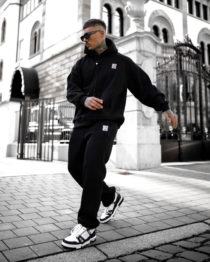 Martin Valen Sigilio oversized black tracksuit mid-body view, kangaroo pocket and white QR code on pants