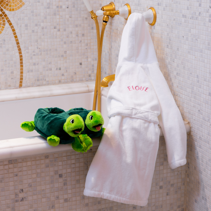 Pair of Skipperdee slippers next to Eloise bathrobe in a bathroom